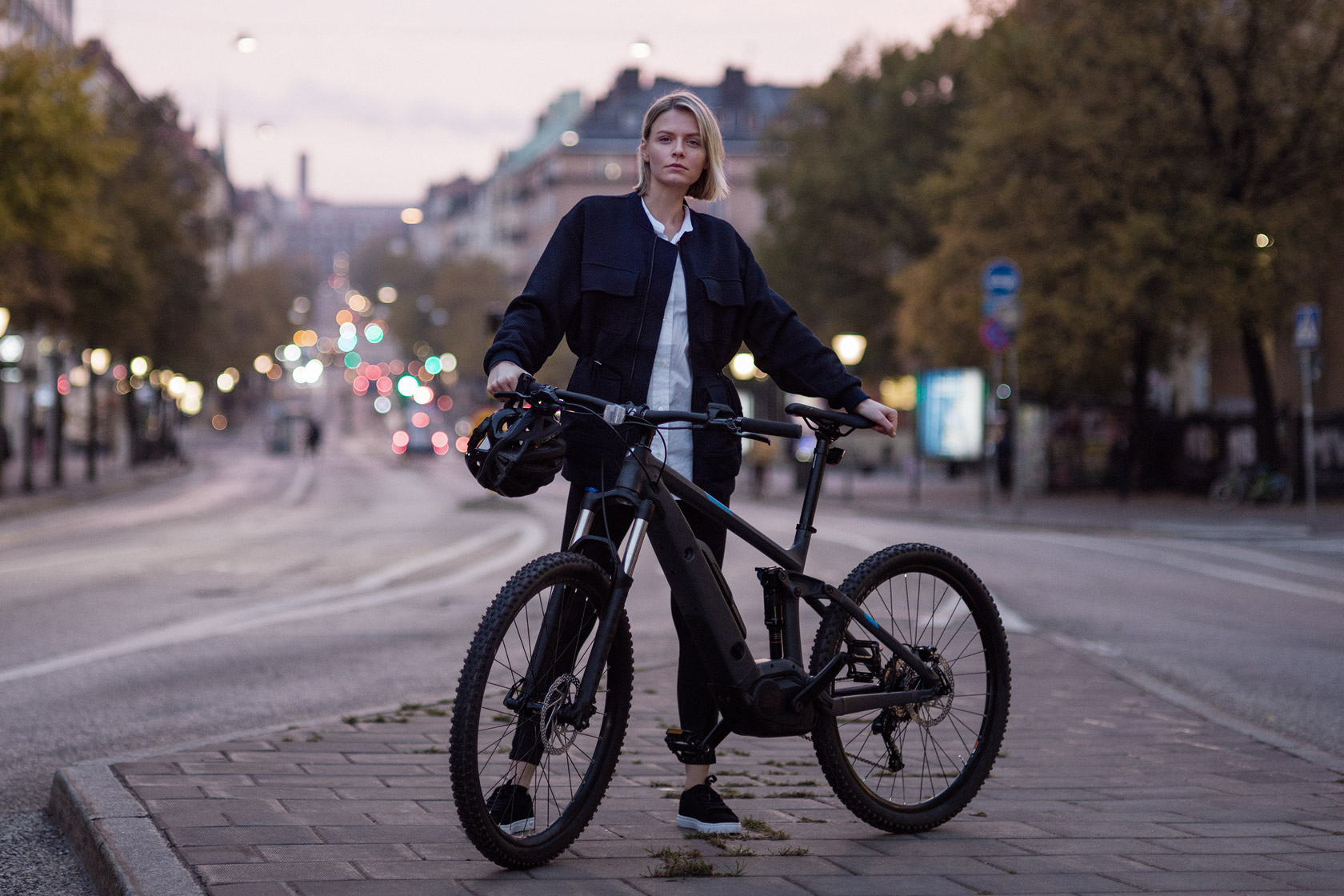 Ung kvinna som står vid sin cykel på en gata i Stockholm