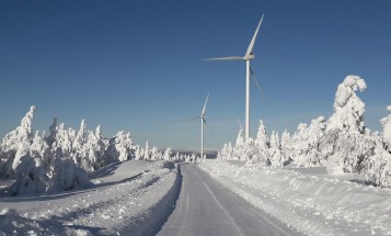 En väg och två vindkraftverk i snötäckt landskap